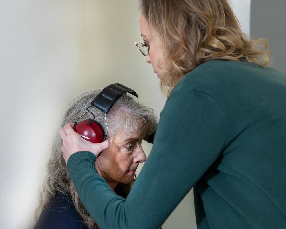 Audiologist placing headphones on a patient for a hearing test